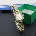 Detailed close-up of a gold square watch with crystal accents and green box - Square Gold White