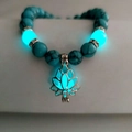 Luminous turquoise yoga energy bead bracelet with silver hollow lotus pendant in low light - Blue Turquoise Cyan Glow