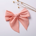 Detailed view of a pink linen cotton bow hair clip on a minimalist white background - Watermelon red