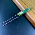 Detailed macro view of a green crystal hair fork with silver wire wrapping and dual wavy pins - Yellow & Green