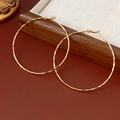 Vista macro de pendientes de aro dorados con textura de ondas martilladas en el metal - Poste de pendiente de plata - Dorado - 6cm