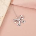 Gros plan d'un pendentif nœud en argent poli sur une chaîne fine et fond élégant - Style Nœud Papillon 5 (5#)