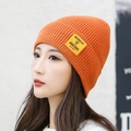 Bright orange ribbed knit beanie for men and women featuring a yellow square logo patch - Orange