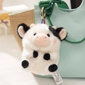 Detail of plush cow keychain with black spots and gold metal ring on a canvas bag - Cow