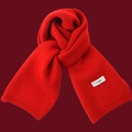 Close-up of a soft red knitted winter scarf with a white brand label and elegant knot detail - Bright Red (FEIDING Label)