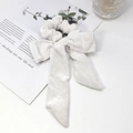 Detailed view of a creamy white velvet scrunchie with a large bow and long streamers - Velvet / Long Ribbon Bow Style / White