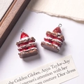 Macro shot of two resin strawberry chocolate cake charms with realistic textures - Dark Brown + Red Filling
