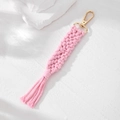 Detail of pink handmade macrame keychain with woven texture, golden clasp and soft fringe - Pink