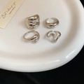Close-up of four silver irregular lava texture rings set on a white ceramic plate - Style 11 (Set of 4)