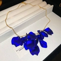 Detalle de collar dorado con flecos y colgantes de pétalos azul oscuro mate en estuche - Azul