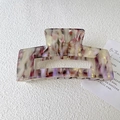 Macro detail of a square marbled purple acetate hair claw clip on a white textured surface - Purple White