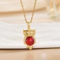 Golden owl pendant necklace with red opal stone against white ceramic background - Gold Owl/Round Red Translucent Stone