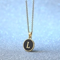 Golden necklace with circular black pendant featuring a serif letter L on a sparkly blue background - Letter L