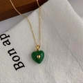 Detailed macro view of a green enamel heart pendant on a delicate gold link chain - Green