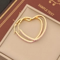 Macro view of gold-plated heart hoop earrings with sparkling pink crystal inlay - Pink