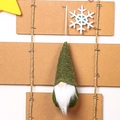 Close-up of a green knitted Christmas gnome ornament with white fur beard hanging on a rope - Green Type C