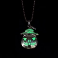 Macro shot of Halloween pumpkin witch pendant glowing green in dark background - Green