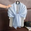 Blue cotton linen scarf with white patterns and tassels, shown tied on a model - Blue