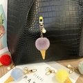 Detailed view of a cute plush ice cream keychain with a pearl charm on a stylish black bag - Single Piece / Purple