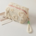 Close-up of plush cream makeup bag with 3D heart pattern and pink zipper handle - Beige