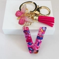 Macro shot of resin letter V keychain with pink stones, gold butterfly and tassel - Rose Red Butterfly Tassel Clip / Letter V