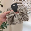 Chouchou à froufrous kaki à pois noirs tenu à la main dans une boutique de bijoux - Chouchou en Coton et Lin à Points Noirs Kaki