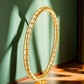 Aro de fitness segmentado dorado mate contra pared verde oscuro con luz natural - Dorado
