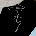 Elegant silver tassel long necklace with a bow knot design on black velvet background - Alloy