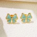 Gros plan de boucles d'oreilles nœuds dorées avec texture marbre bleu clair sur blanc - Bleu