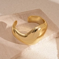 Detailansicht eines skulpturalen goldenen Armreifs mit polierter Oberfläche - Gold