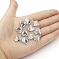 Macro shot of silver heart-shaped fish scale resin sequins held in a palm for DIY crafts - 12mm Silver Iridescent