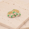 Retro golden hoop earrings with green enamel and pink daisy pattern on stone background - Green