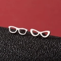 Detailed macro shot of asymmetrical silver eyeglass studs on a dark textured surface - Steel
