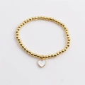 Detail of gold beaded stretch bracelet featuring a white enamel heart charm pendant - White
