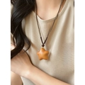 Close-up of wooden star pendant with woven cord on a linen garment for a boho look - Star / Brown
