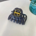 Top-down view of a large dark grey pumpkin hair claw clip with a strong golden metal spring - Light Silver Grey
