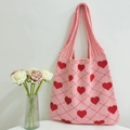 Close-up of pink knitted tote bag with red heart pattern and diamond grid texture - Pink and Rose Red