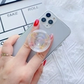 Detail of telescopic phone grip with gold galaxy planet design on a grey smartphone - Transparent Planet