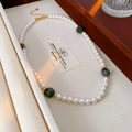 Detail of irregular white pearl necklace with green gemstones on beige fabric - White Pearl With Green Stone (Gold Clasp)