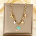 Detailed macro view of marine ocean charms with starfish and pearls on a gold link bracelet - Dolphin Pearl Shell Style (KN292150-SXSJ)