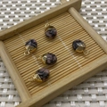 Five faceted tiger eye stone oval pendants with gold-plated loops on a bamboo tray - Rhodonite with Black Lines
