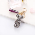 Close-up of sparkling rhinestone bear keychain with purple plaid strap and gold metal hardware - Mixed Purple