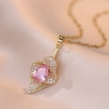 Macro detail of a gold heart pendant necklace with pink pear-cut gemstone and crystals - X0066 Pink Teardrop Trumpet Flower Style