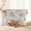 Beige corduroy makeup bag with blue bow prints shown in hand against a soft background - Beige Blue Bow (PQ374618)