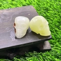 Carved crystal skulls in translucent white and yellow-green stone on a wooden base - Afghan Jade