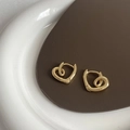 Détail de boucles d'oreilles cœur torsadé en cuivre plaqué or sur fond en cuir - Doré
