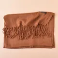 Detail view of coffee brown cashmere scarf with long fringe and decorative brand label - Coffee