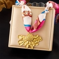Dettaglio collana in nastro di seta con ciondolo a fiore dorato su portagioie - Ciondolo Fiore Rosa Blu (N3604)