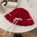 Red knit bucket hat with white bow tie decoration on a minimalist white table setting - Hat / Red