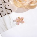 Detalle de un colgante de lazo dorado con circonitas rosas sobre el fondo de una revista - Rosa